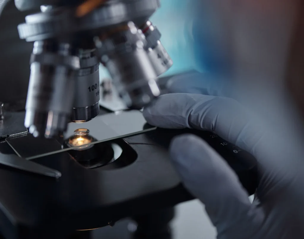 Researcher placing a sample slide under a laboratory microscope