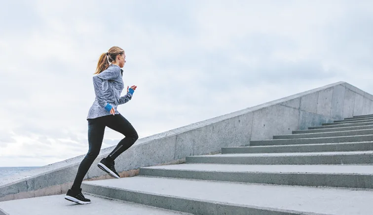 Woman running up concrete stairs by the sea
